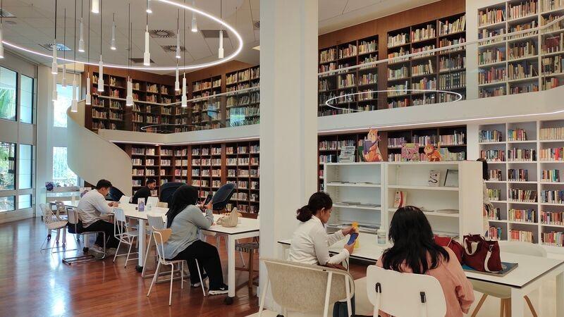 Modern public library reading area with people studying