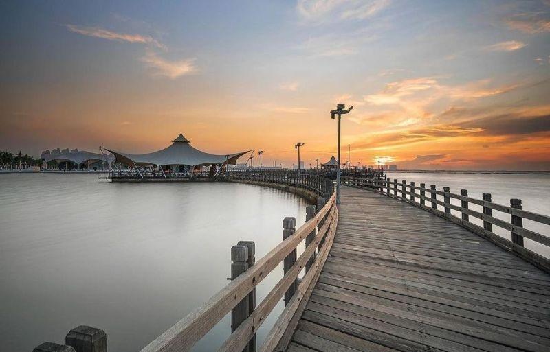 Curved wooden boardwalk to waterfront pavilion at sunset