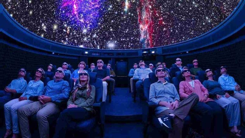 Audience in planetarium wearing 3D glasses watching stars