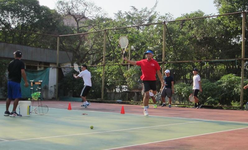 Group of players practicing tennis drills on outdoor court