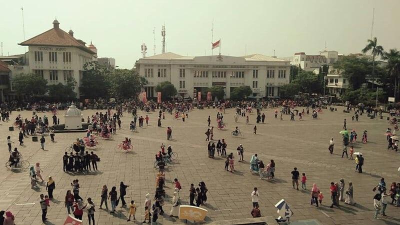 crowded city square with people and bicycles
