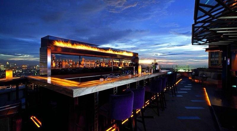 Rooftop bar with flaming backlit counter and city skyline