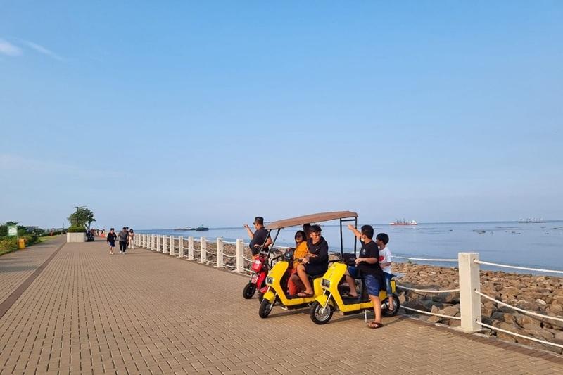 People on yellow electric tricycles at seaside promenade