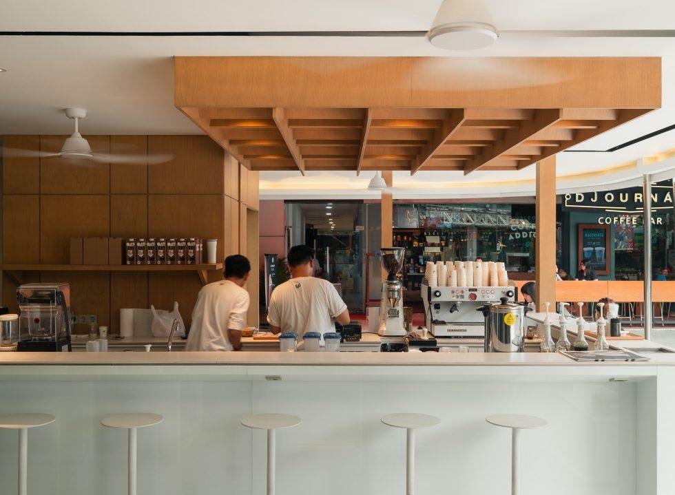 Two baristas working at minimalist white coffee bar