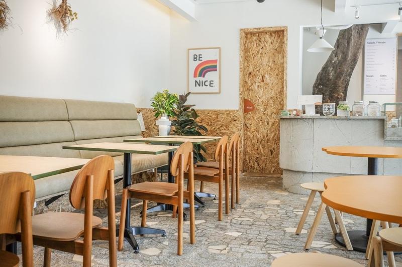 Cozy cafe interior with wooden chairs and Be Nice poster