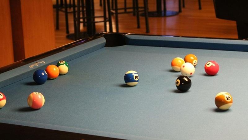 Blue pool table with scattered billiard balls