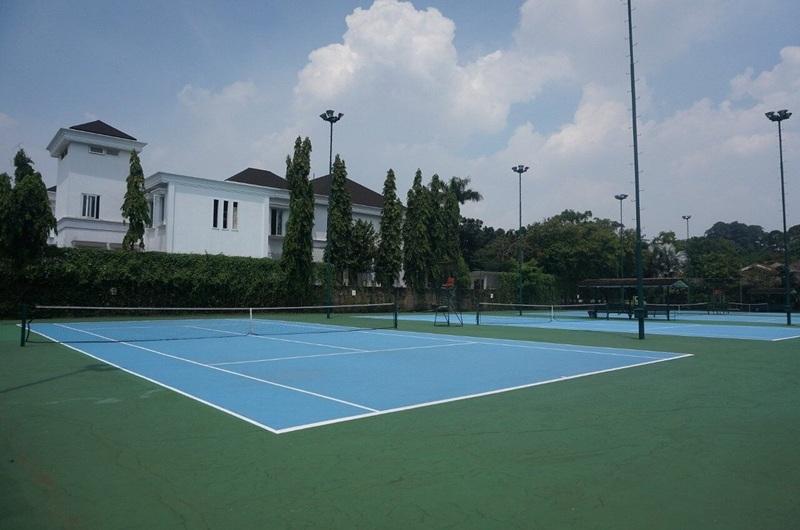 Empty blue tennis courts with white house background