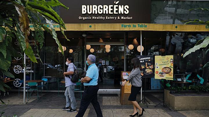 Burgreens logo on eatery storefront with pedestrians