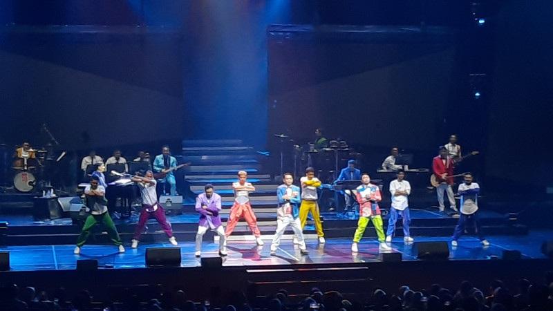Stage concert with ten dancers in colorful outfits