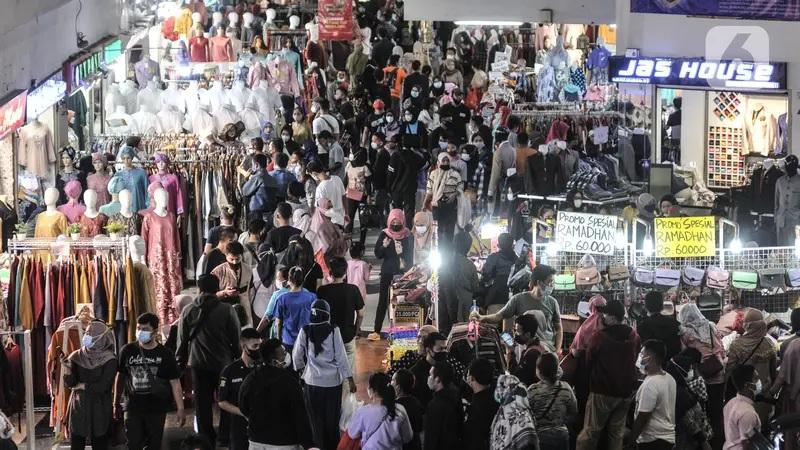 Crowded indoor market with clothing stalls and shoppers
