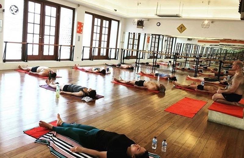 yoga class participants resting in mirrored studio