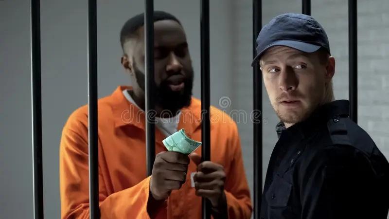 Prisoner in orange handing money to officer through bars