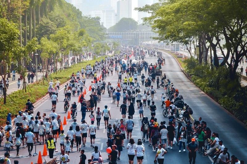 Large group of people walking and running on city street