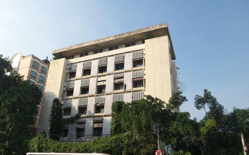 Concrete office building facade with trees and vines