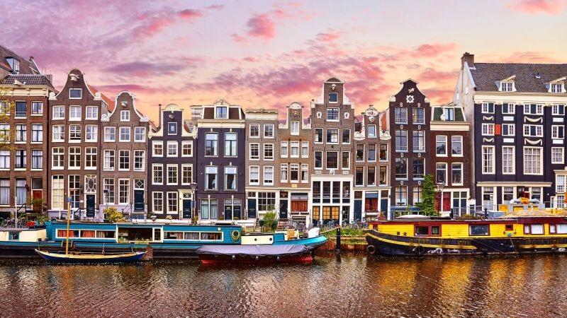 Amsterdam canal houses and colorful houseboats at sunset