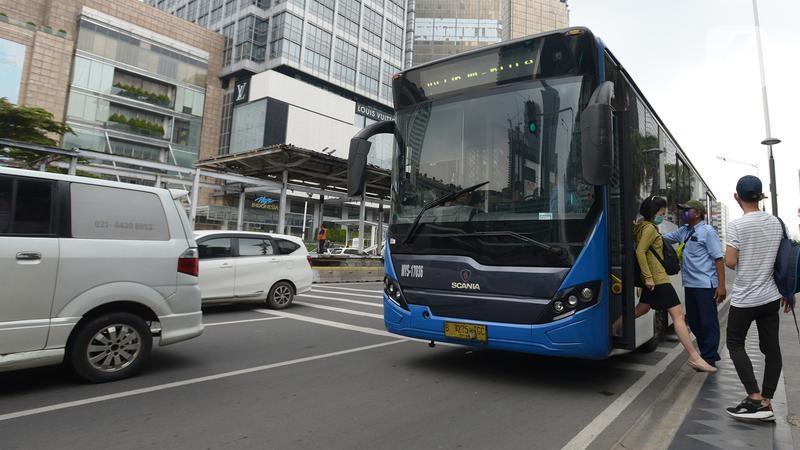 Blue Scania city bus picking up passengers at curb