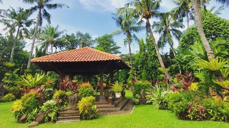 Tropical garden gazebo with tiled roof and palms