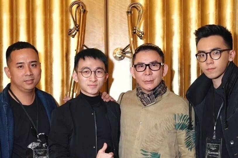 Four men posing by gold curtain