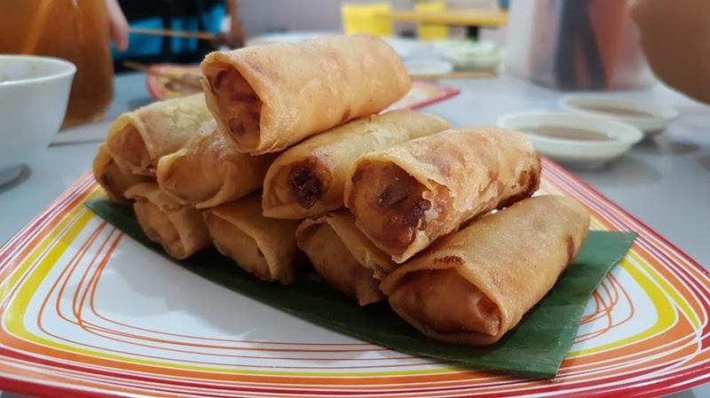 Fried spring rolls stacked on plate with dipping sauce