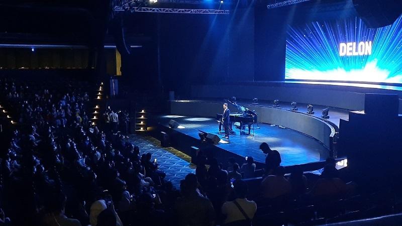 Performer at piano with DELON logo on stage