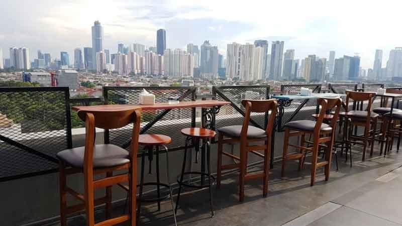 Rooftop bar with wooden high chairs and city skyline