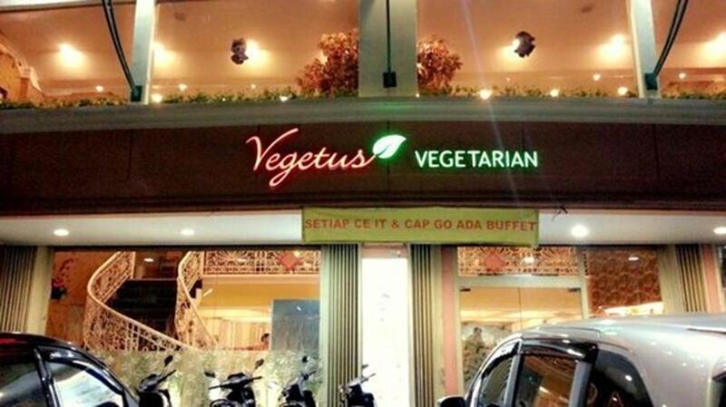 Vegetus vegetarian restaurant logo on storefront at night