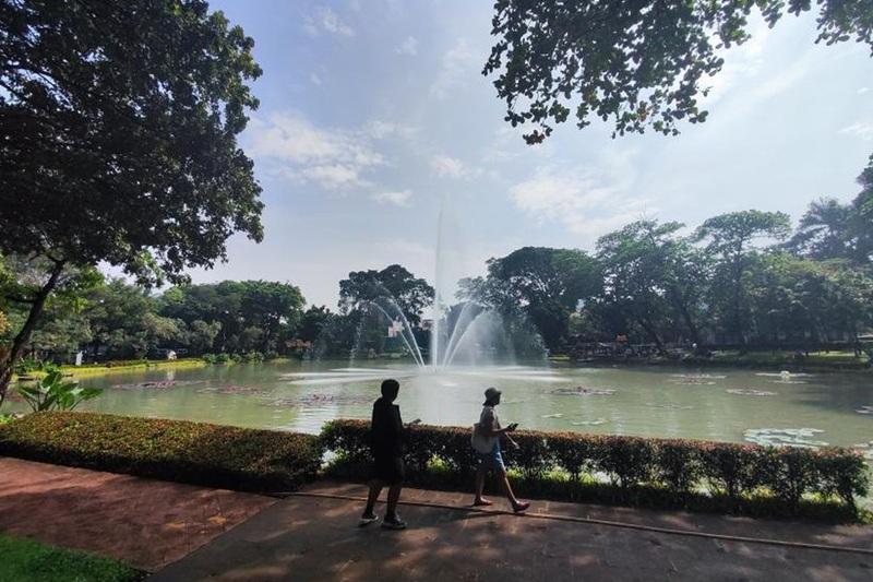 Two people walking by park lake with fountain