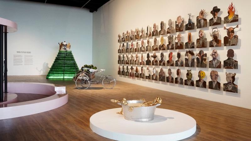 museum gallery with wall of portraits and sculptures