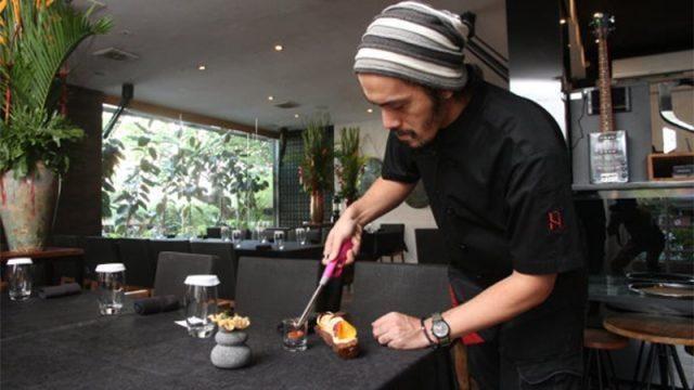 Chef torching dessert at restaurant table