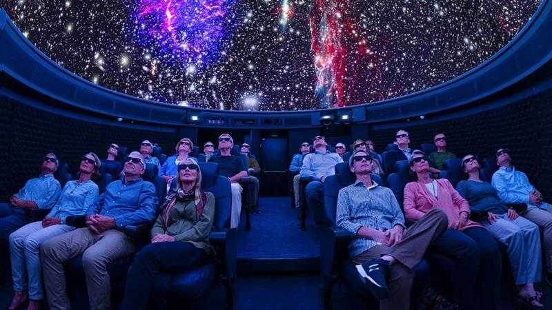 Planetarium audience wearing 3D glasses under starry dome