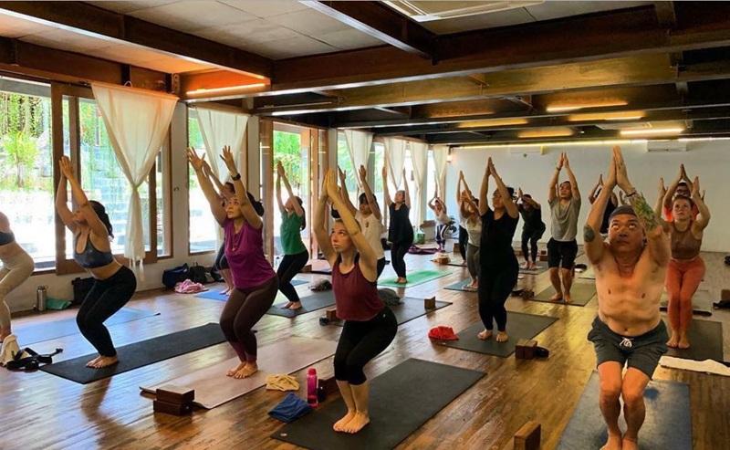 Group yoga class in studio doing chair pose