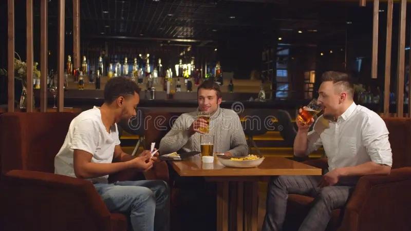 Three men drinking beer at a bar table