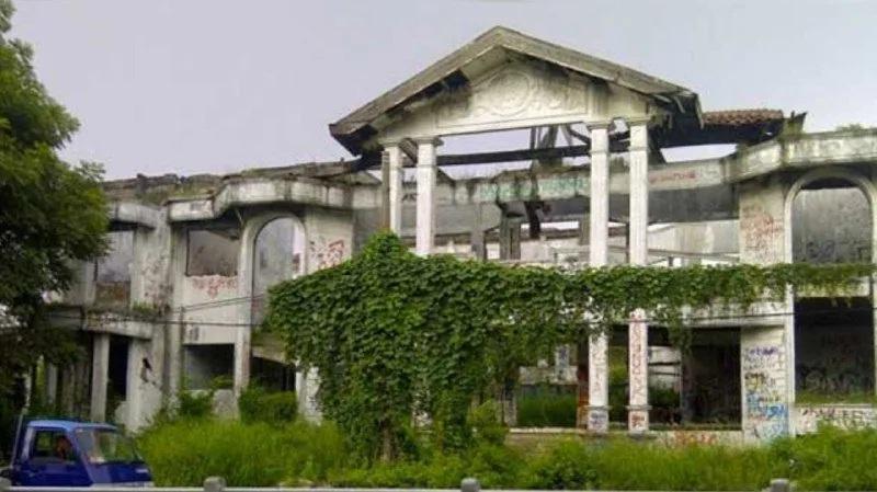 Overgrown abandoned mansion with graffiti and pillars