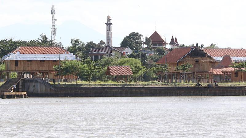 Riverside village with stilt houses and mosque tower