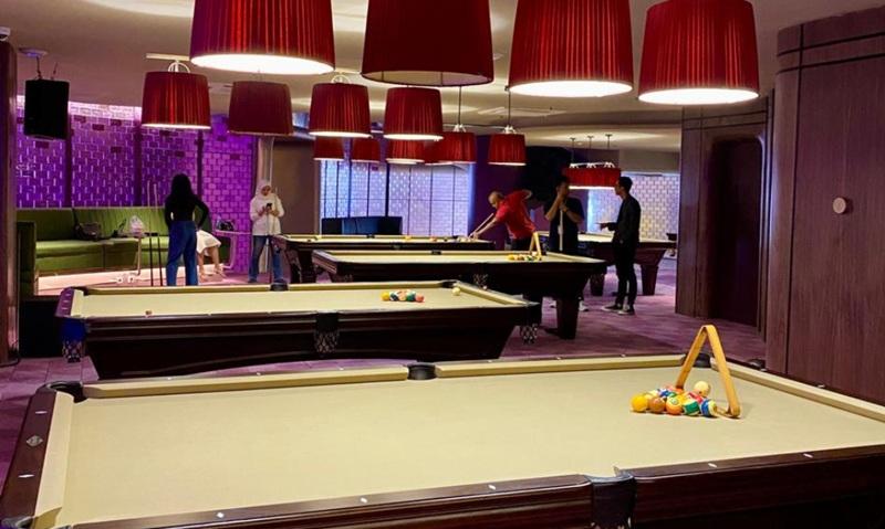 Pool hall interior with multiple tables and red lamps
