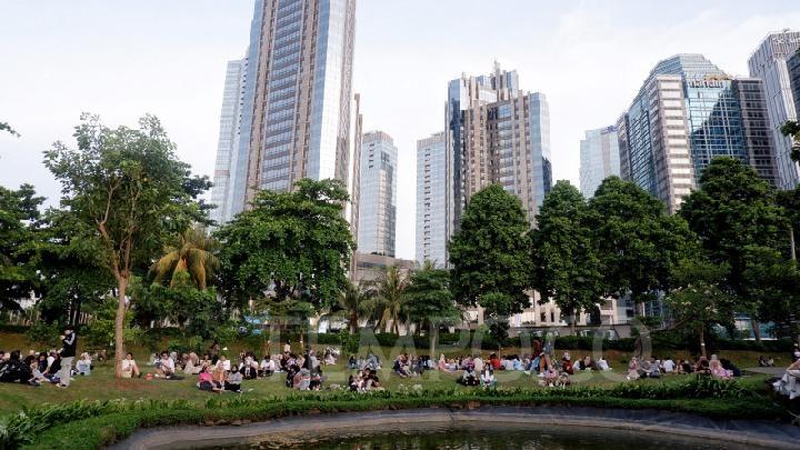 People picnicking in urban park with skyscraper skyline