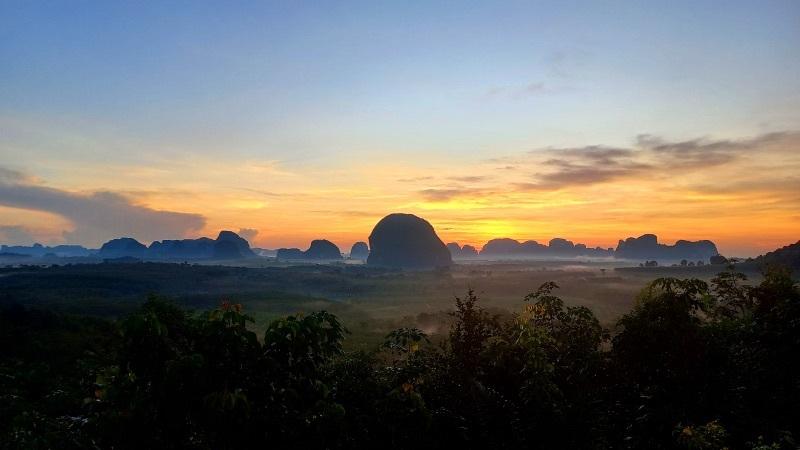 sunrise over misty karst hills with foreground trees