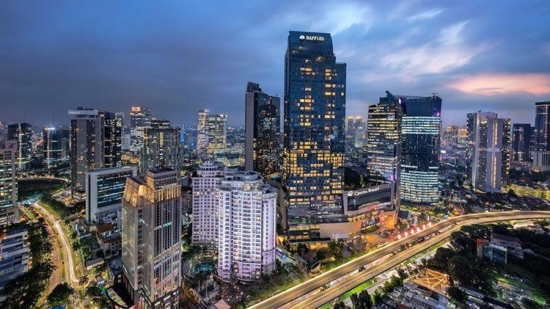 Cityscape at dusk with illuminated skyscrapers and highway