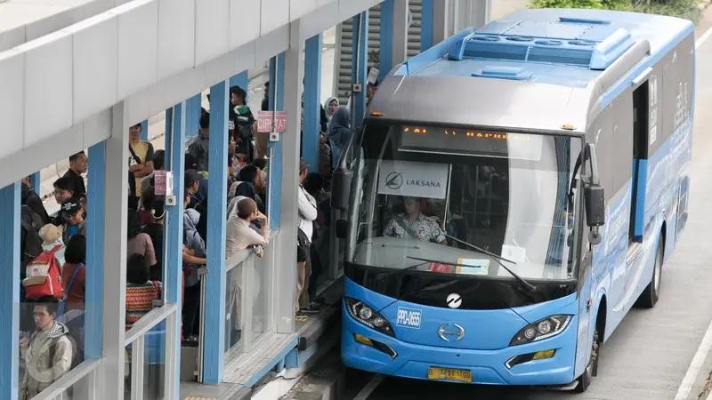 Blue bus boarding crowded station platform