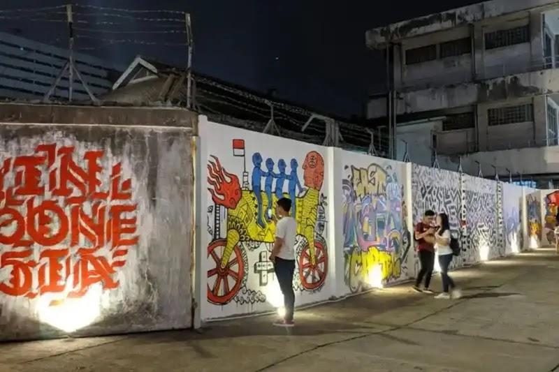 Night street murals on wall with people viewing graffiti