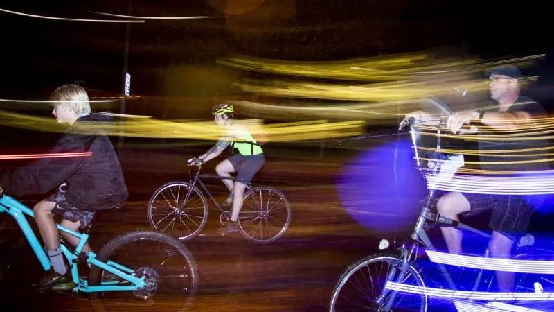 Cyclists at night with yellow and blue light trails