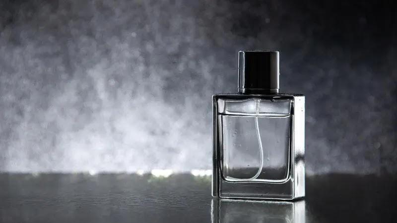 clear rectangular cologne bottle on reflective surface
