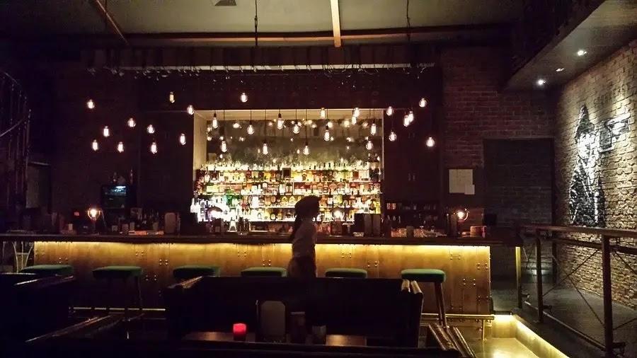 Dim bar interior with hanging lights and silhouette