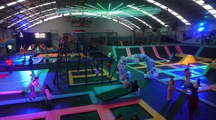 Indoor trampoline park with neon lights and people