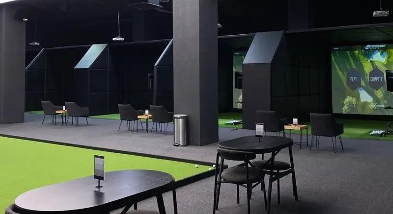 Indoor golf simulator bays with seating and tables