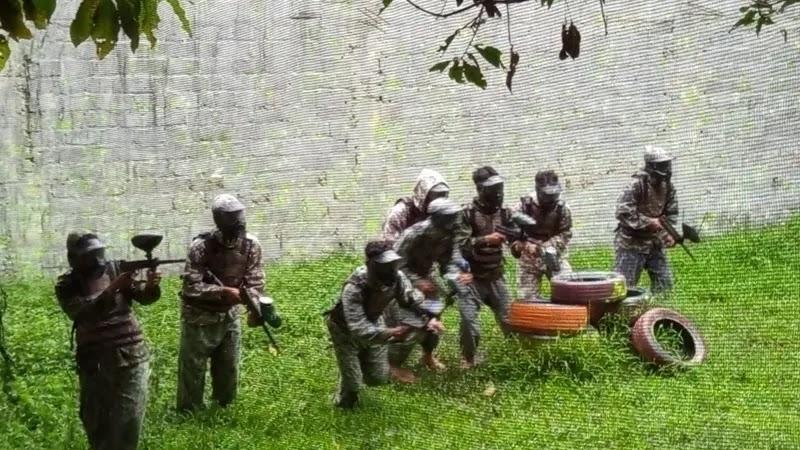 Paintball players in camouflage near tire barricade