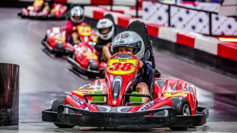 Child driving red go-kart number 38 on indoor track