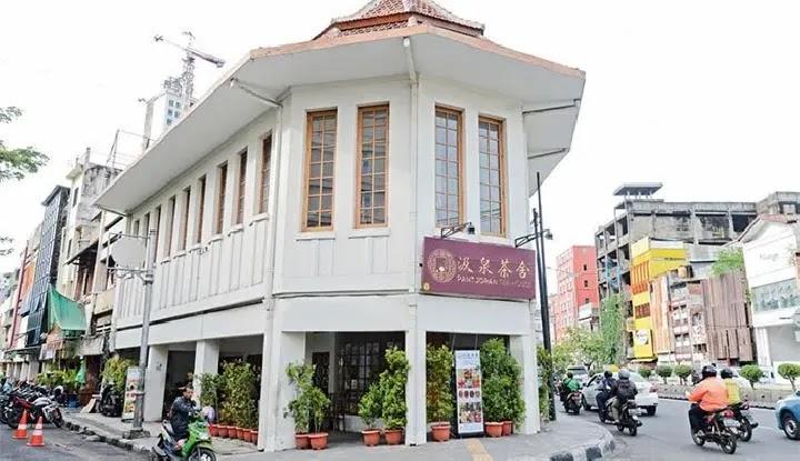 white corner building with maroon sign and potted plants