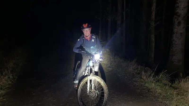 Cyclist mountain biking at night with bright headlight