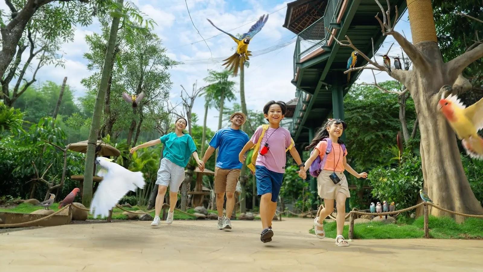 Family of four walking in aviary with colorful birds